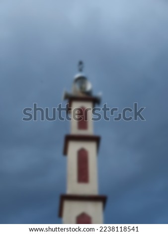 defocused background of lighthouse of the mosque with four loudspeakers under a blue sky