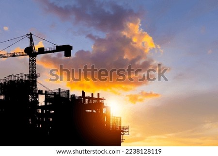 Silhouettes of building construction site with clipping path and construction cranes with blurred sunset background and copy space