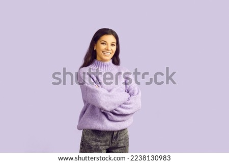 Portrait of smiling young Latin woman isolated on violet studio background pose with arms crossed. Happy millennial ethnic girl feel joyful and excited look at camera. Happiness and ethnicity.