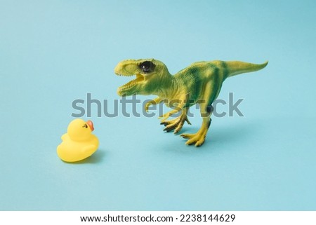 T-rex with yellow rubber duck on blue background.