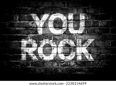 You rock lettering on brick wall. Cool expression for a man, motivational card. You Rock poster with grunge text design, mixed media.