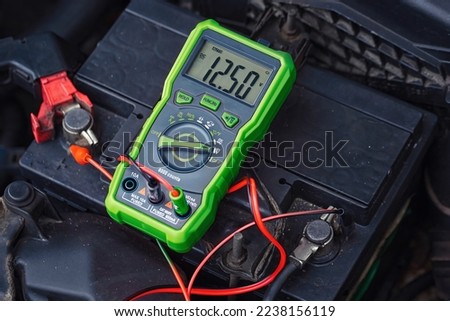 Measurement of car battery voltage. Good car battery, almost fully charged voltage - 12.5V.  Battery capacity tester voltmeter. Check voltage with multimeter. Test battery health Royalty-Free Stock Photo #2238156119