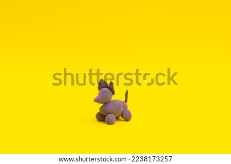 Figurine with clay looks like a dog, purple on a yellow background, children's crafts