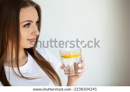 Beautiful youthful lady refreshing herself with lemon water