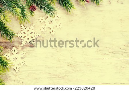 Christmas decorations with fir tree branch and snowflakes on a light wood background. tinting. selective focus on the top branch
