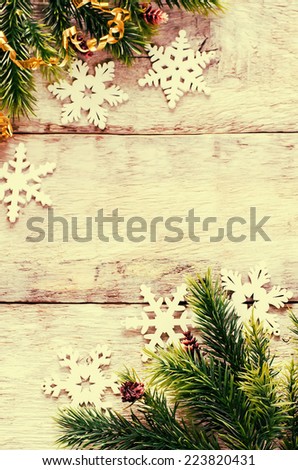 Christmas decorations with fir tree branch and snowflakes on a light wood background. tinting. selective focus on the bottom branch