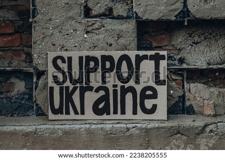 Ukrainian protest against war with banner, placard  with inscription message text Support Ukraine, ruined city background. Crisis, peace, Russian aggression invasion concept. anti-war demonstration.