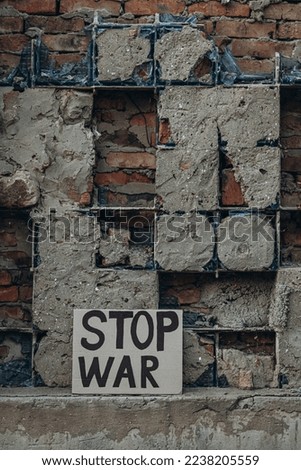 Ukrainian protest against war with banner placard  with inscription message text STOP WAR, ruined city background. Crisis, peace, Russian aggression invasion concept. anti-war demonstration.
