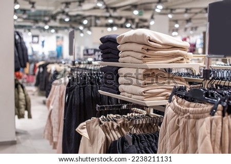 A set of beige clothes in the store on the shelf. Pants are hanging on a hanger Royalty-Free Stock Photo #2238211131
