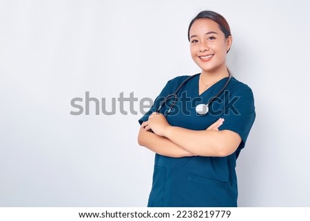 Smiling young Asian woman nurse wearing blue uniform with stethoscope cross arms chest and looking at the camera isolated on white background. Healthcare medicine concept Royalty-Free Stock Photo #2238219779