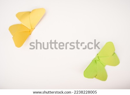 origami butterflies in yellow and green creating a picture frame on a white background