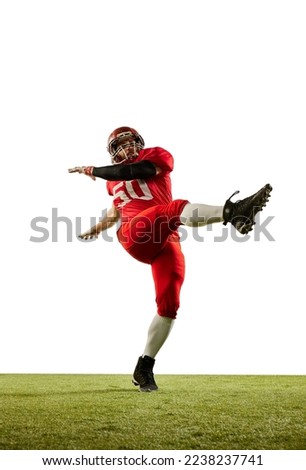 Kick the ball. Professional american football player in sports uniform and protective helmet training with ball isolated over white background. Sport, team, competition, championship concept Royalty-Free Stock Photo #2238237741