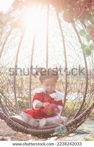 Pretty little kid girl wears Christmas dress playing snow in the park. beautiful baby girl feeling happy on blur background. Christmas day and happy new years concept. Copy space for text.