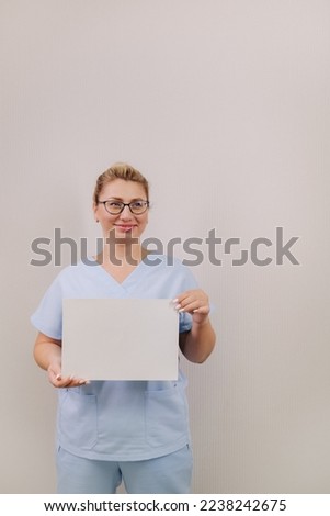 Portrait of a female doctor in a blue robe holding a white blank sheet.