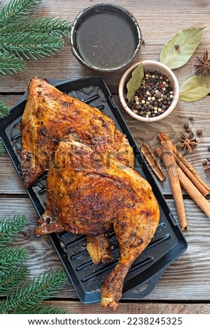 Baked chicken legs in spices in a grill pan, on a wooden background. Christmas dinner, meeting the new year.