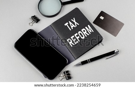 TAX REFORM text written on a black notebook with smartphone, magnifier and credit card