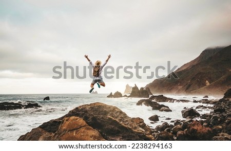 Happy man with backpack jumping on nature background - Successful hiker enjoying freedom climbing rocks outdoors - Adventure, journey, freedom and sport concept Royalty-Free Stock Photo #2238294163