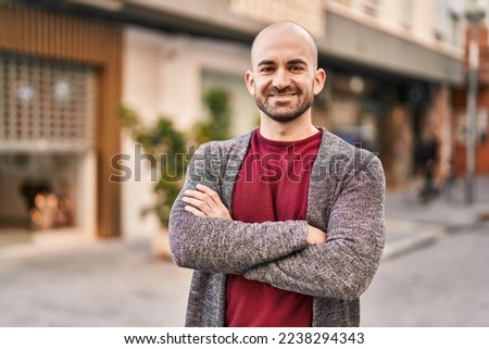 Young man smiling confident standing with arms crossed gesture at street
