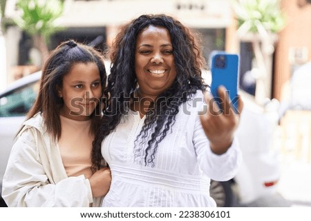 Mother and daughter hugging each other make selfie by smartphone at street