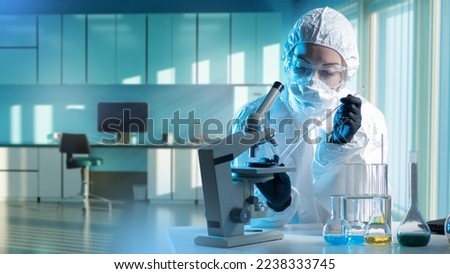 Woman virologist. Working with hazardous infections. Girl in protective suit. Virologist sits at desk with test tubes and microscope. Experiments with pathogens in lab. Virologist doing science Royalty-Free Stock Photo #2238333745