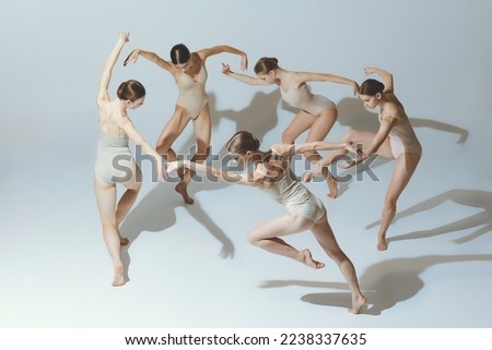 Group of young girls, ballet dancers performing, posing isolated over grey studio background. Circle movements. Concept of art, beauty, aspiration, creativity, classic dance style, elegance Royalty-Free Stock Photo #2238337635