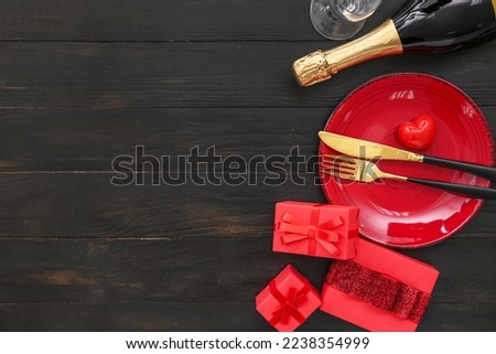 Table setting for Valentine's Day with gifts on black wooden background