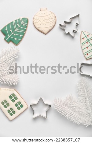 Frame made of Christmas cookies, cutters and fir branches on light background, closeup