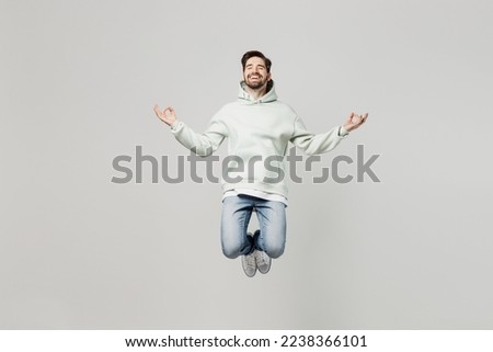 Full body young man wear mint hoody look camera hold spreading hands in yoga om aum gesture relax meditate try to calm down isolated on plain solid white background studio. People lifestyle concept