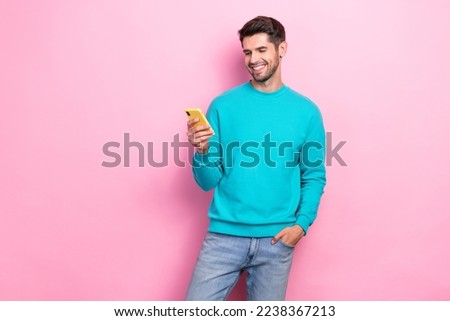 Photo of young smiling satisfied glad cheerful handsome student guy use his smartphone browsing youtube video isolated on pink color background