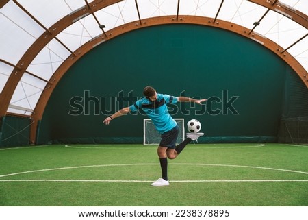 Cinematic image of a soccer freestyle player making tricks with the ball on a artificial grass court indoor. Concept about sport and people lifestyle	 Royalty-Free Stock Photo #2238378895