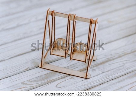Close-up of small, miniature wooden self-made glued two children's slides, swing from a playground constructor kit. Photography, design.