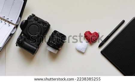 Graphic designer workstation with dslr, lens, agenda, stylus and heart printed in 3d