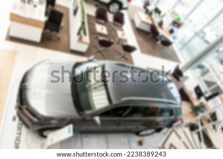 Blurred background of new cars and visitors displayed in showroom