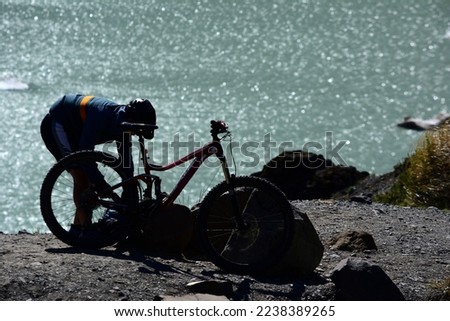 mountain biker preparing his bike with lake in the background. bicycle tourism