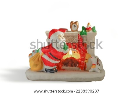 figurine of santa claus next to a fireplace in ceramic, isolated on white background