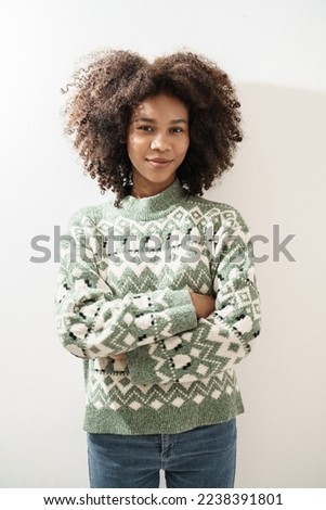Vertical image Portrait of African American young woman in knitted sweater posing on white background. Girl smiling while looking at camera.