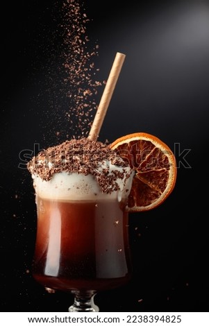 Chocolate cocktail with whipped cream sprinkled with chocolate chips and garnished with a dried orange slice. Copy space.