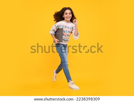 Teenager school girl hold notebook laptop. Run and jump, jumping kids. School children on isolated studio background.