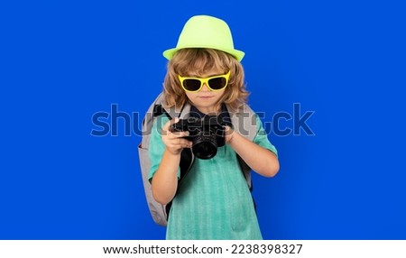 Child traveller photographer with camera taking pictures in studio. Kid photo camera. Lifestyle travel concept.