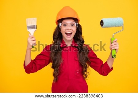 Excited teenager girl. Building, construction and profession concept - smiling little girl in protective helmet and safety vest with paint roller.