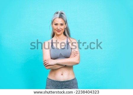 beautiful middle aged woman making sport at the gym.  female model posing for a body positive and self acceptance concept photoshooting on colored backgrounds Royalty-Free Stock Photo #2238404323