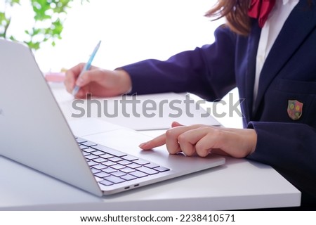 A girl who studies using a computer.

The notes are written in English and their translations in Japanese. Royalty-Free Stock Photo #2238410571