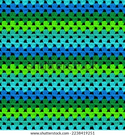 Bright seamless knitted texture. The pattern is crocheted from contrasting acrylic yarn. Zigzag shapes. African motives. 
