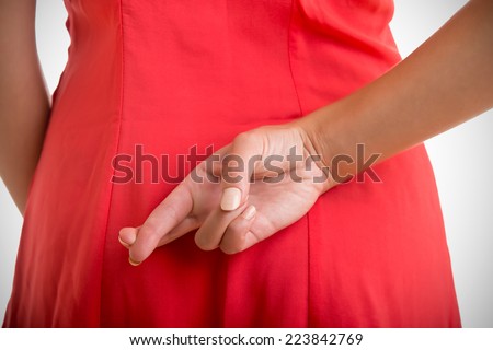 Close up of crossed fingers behind a woman's back Royalty-Free Stock Photo #223842769