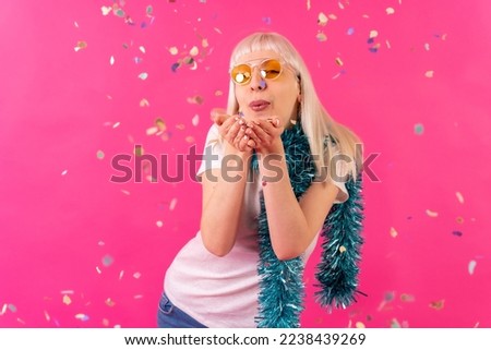 Birthday confetti party with sunglasses, blonde caucasian girl on pink background studio