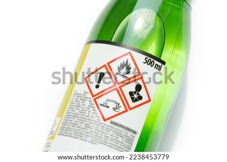 A green bottle of highly corrosive flammable chlorinated rubber nitro solvent with printed on warning symbols label, sticker. Dangerous chemical substances abstract concept, closeup, detail, nobody