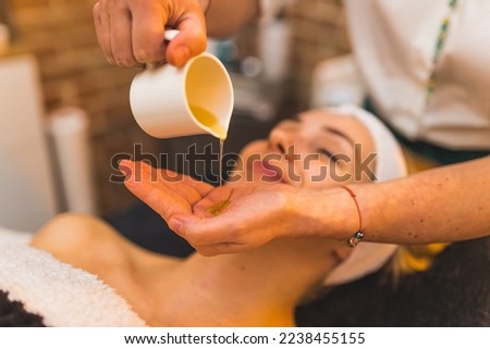 closeup view of a cosmetologist taking oil on her hand to put it on a client's face, spa treatment concept. High quality photo