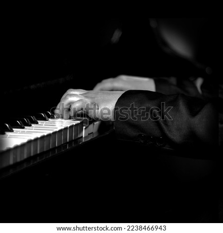 Pianist male hands playing music on piano keys.