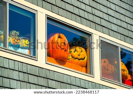 Holloween decorations in window with gray wooden building and white accent paint on holiday in the suburbs or city