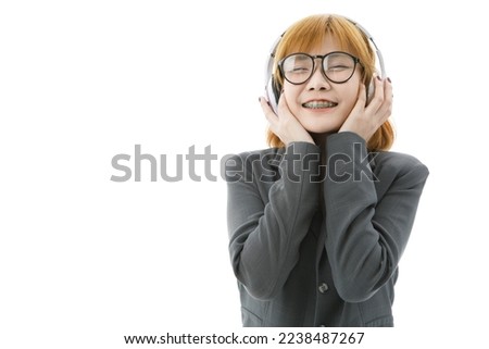 Isolated closeup cutout studio shot Asian young university female student in uniform and eyeglasses standing smiling holding headphone closed eyes listening to music song playlist on white background.
